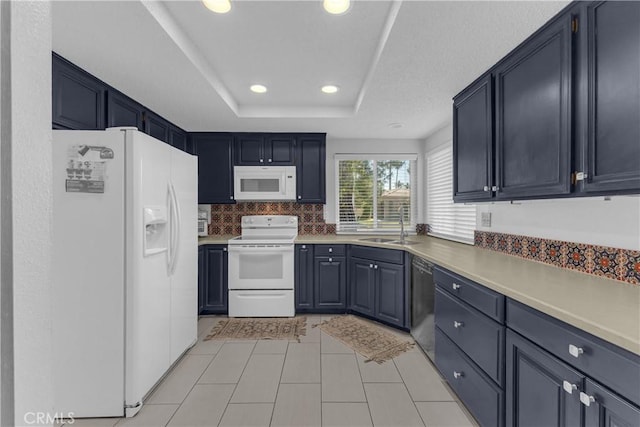 kitchen with white appliances, a sink, a tray ceiling, light tile patterned floors, and recessed lighting