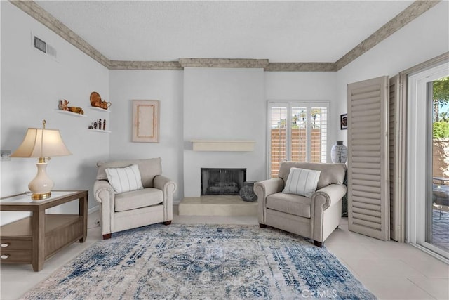living area with a fireplace with raised hearth, tile patterned floors, and a textured ceiling