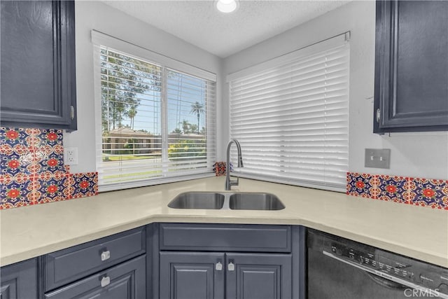 kitchen featuring dishwasher, a sink, light countertops, backsplash, and a textured ceiling