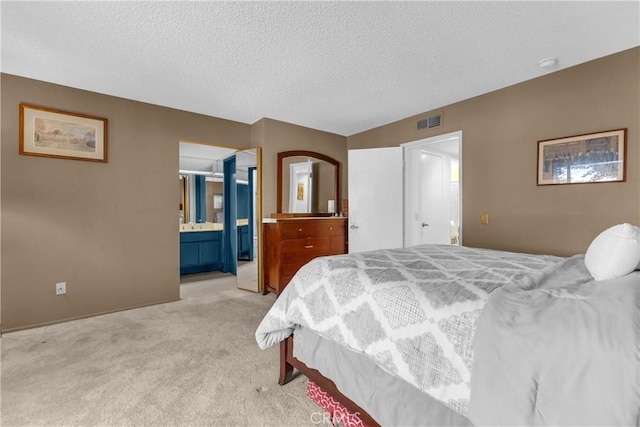 bedroom featuring light colored carpet, a textured ceiling, and ensuite bathroom