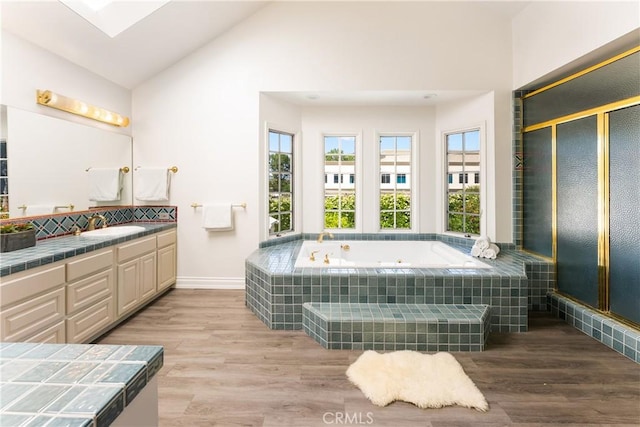 23721 Sarda Rd, Valencia, CA 91355 - bathroom featuring a tub with jets, vanity, wood finished floors, a stall shower, and high vaulted ceiling