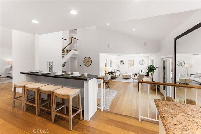 23721 Sarda Rd, Valencia, CA 91355 - kitchen featuring light wood finished floors, a kitchen breakfast bar, high vaulted ceiling, open floor plan, and recessed lighting