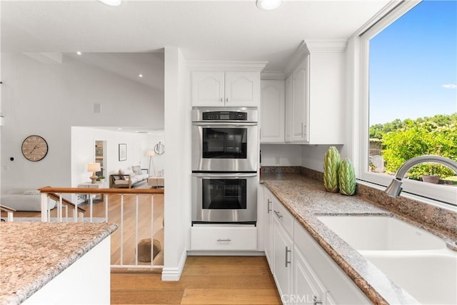 23721 Sarda Rd, Valencia, CA 91355 - kitchen featuring stainless steel double oven, light wood-type flooring, white cabinets, light stone countertops, and recessed lighting