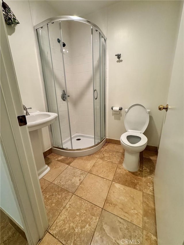bathroom featuring a shower stall, baseboards, and toilet