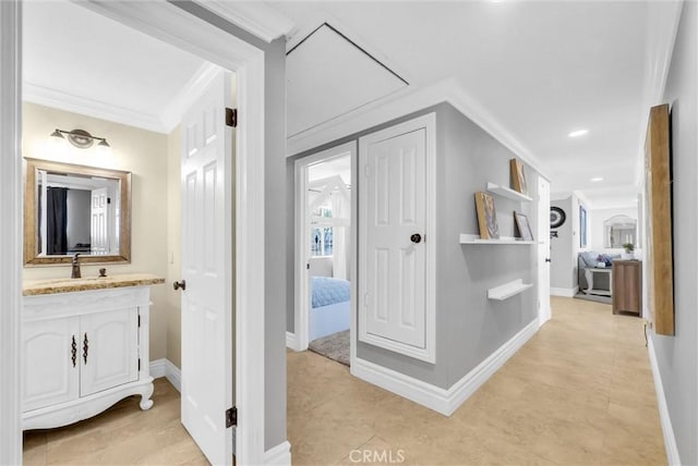 hallway featuring ornamental molding, baseboards, a sink, and light tile patterned floors