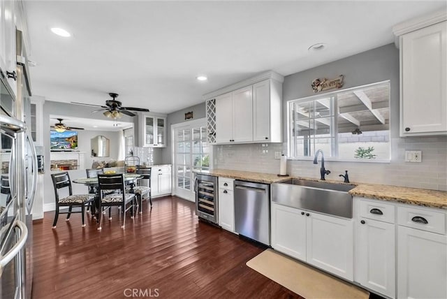 kitchen with a sink, stainless steel dishwasher, wine cooler, ceiling fan, and white cabinetry