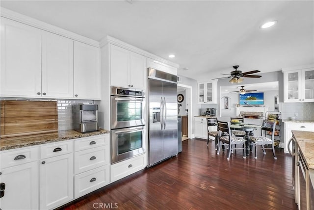 kitchen with stainless steel appliances, white cabinets, decorative backsplash, a ceiling fan, and recessed lighting
