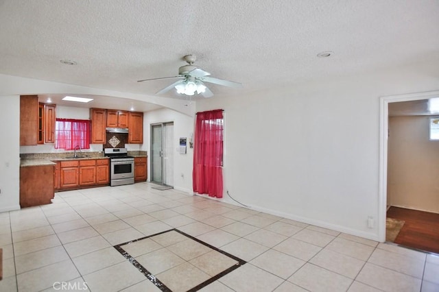 2851 Webster Ave, Long Beach, CA 90810 - kitchen featuring stainless steel electric range oven, a sink, brown cabinetry, light countertops, and under cabinet range hood