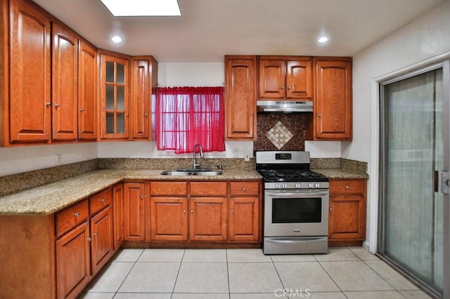 2851 Webster Ave, Long Beach, CA 90810 - kitchen featuring stainless steel range with gas stovetop, a sink, under cabinet range hood, brown cabinets, and glass insert cabinets
