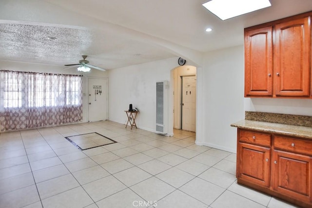 2851 Webster Ave, Long Beach, CA 90810 - unfurnished living room featuring a heating unit, arched walkways, light tile patterned floors, a ceiling fan, and baseboards