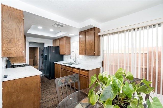 25176 Wendy Way, Moreno Valley, CA 92551 - kitchen with a sink, a raised ceiling, brown cabinets, light countertops, and black fridge with ice dispenser