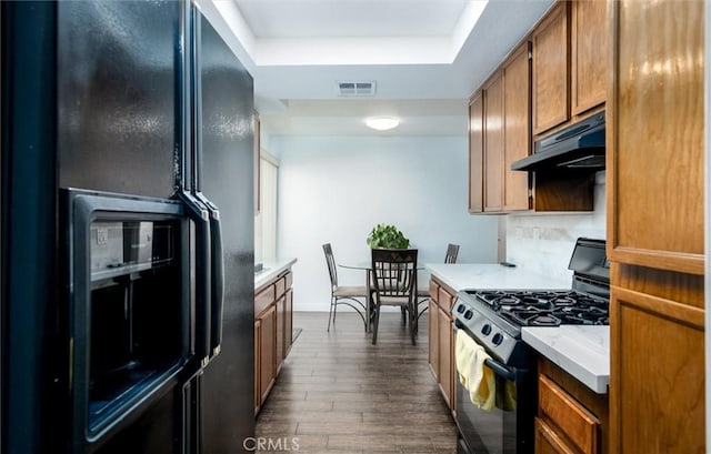 25176 Wendy Way, Moreno Valley, CA 92551 - kitchen featuring black appliances, a raised ceiling, brown cabinetry, light countertops, and dark wood-style floors