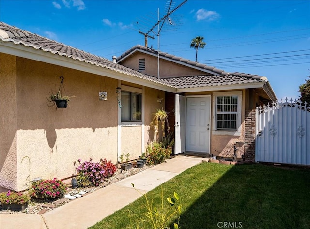 25176 Wendy Way, Moreno Valley, CA 92551 - view of exterior entry featuring stucco siding, a lawn, a tile roof, and a gate