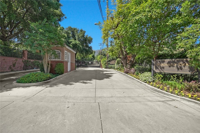 view of concrete street with street lighting, curbs, a gate, and a gated entry
