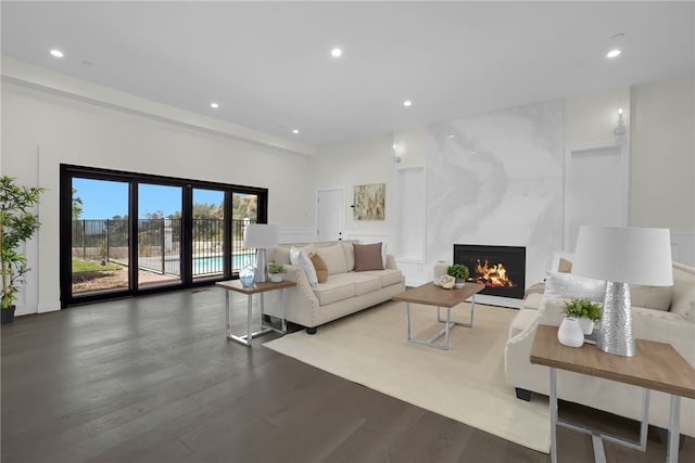 living area with wood finished floors, a premium fireplace, and recessed lighting