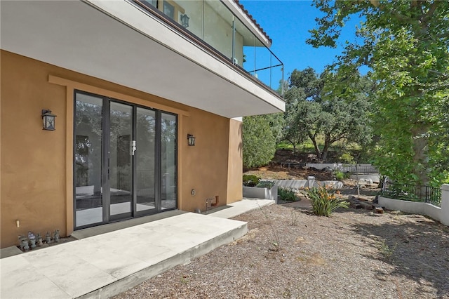 view of exterior entry featuring stucco siding and a patio area