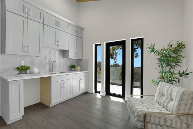 kitchen featuring a sink, light countertops, decorative backsplash, and dark wood-style floors