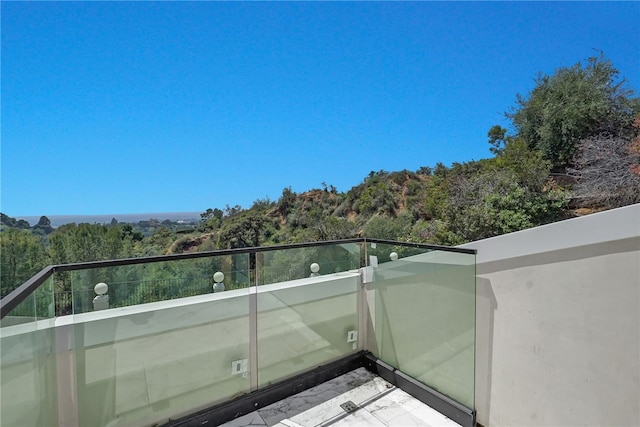 balcony featuring a wooded view