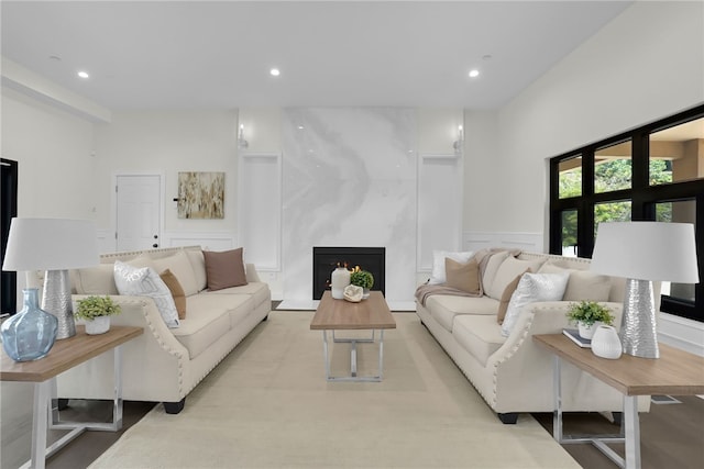 living area with a high end fireplace, a decorative wall, recessed lighting, and a wainscoted wall