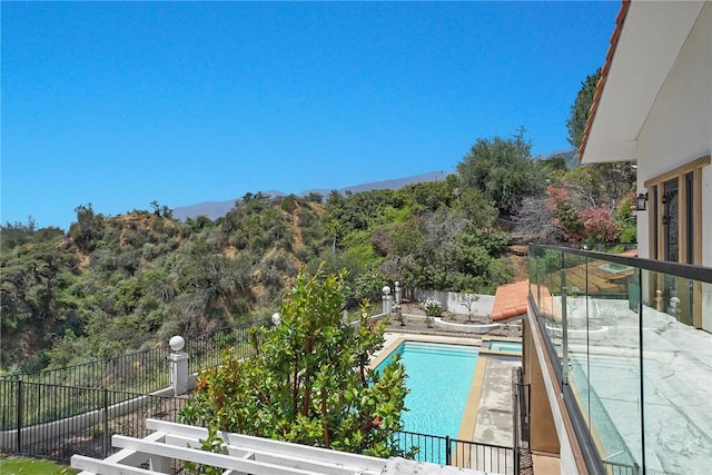 balcony with view of pool, a mountain view, and a pool with connected hot tub