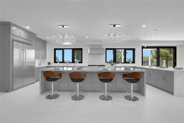kitchen featuring gray cabinets, built in refrigerator, recessed lighting, light countertops, and a chandelier