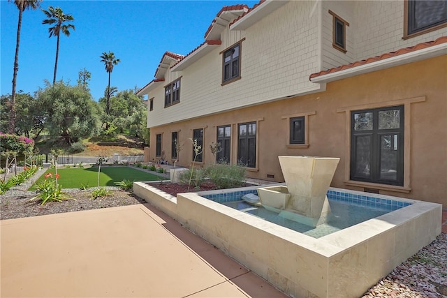 back of house featuring a patio, stucco siding, a lawn, and a tile roof
