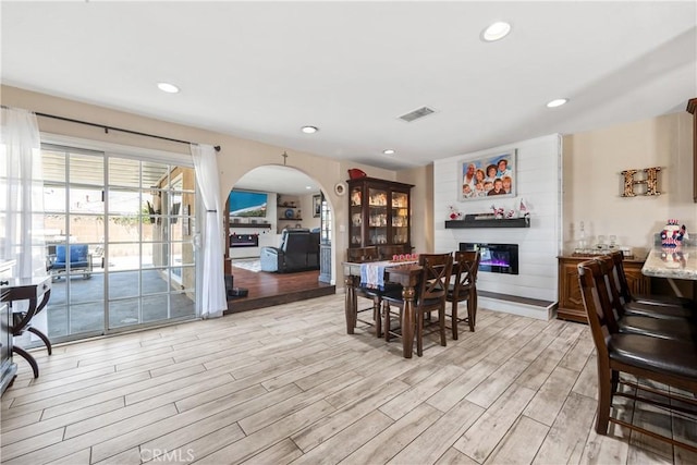 5471 Santa Gertrudes Ave, Garden Grove, CA 92845 - dining area featuring light wood finished floors, a glass covered fireplace, arched walkways, and recessed lighting