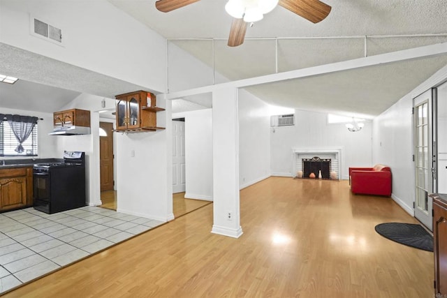 17010 Pocono St, La Puente, CA 91744 - kitchen with black range with gas stovetop, lofted ceiling, light wood-style flooring, a fireplace, and under cabinet range hood