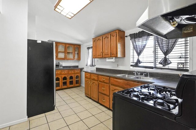 17010 Pocono St, La Puente, CA 91744 - kitchen with freestanding refrigerator, black range with gas cooktop, under cabinet range hood, brown cabinetry, and dark countertops