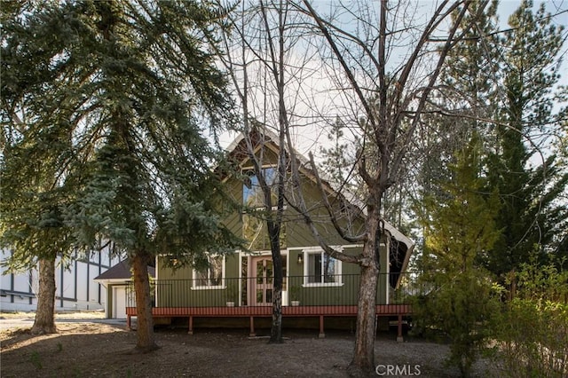 rear view of property with a wooden deck, an attached garage, and driveway