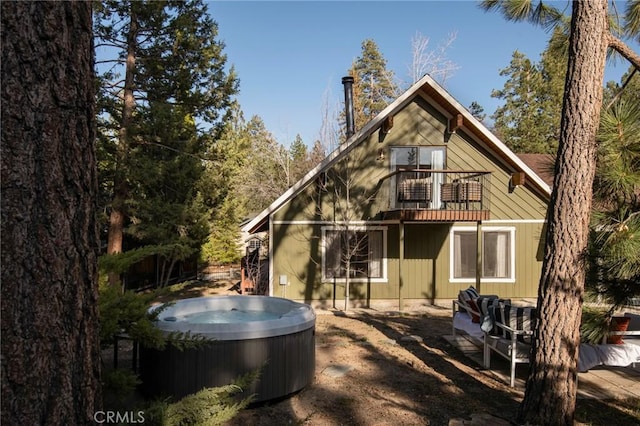 back of house featuring a hot tub and a balcony