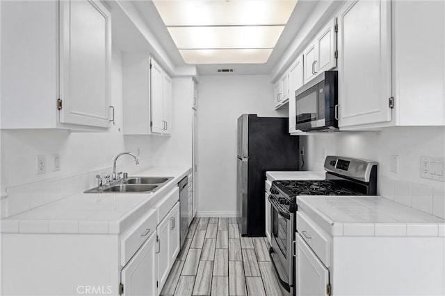 21848 S Vermont Ave Unit 6, Torrance, CA 90502 - kitchen with stainless steel appliances, white cabinetry, tile countertops, and light wood-type flooring