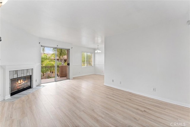21848 S Vermont Ave Unit 6, Torrance, CA 90502 - unfurnished living room with light wood-style flooring, a tile fireplace, and a chandelier