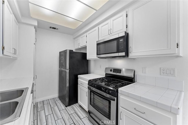 21848 S Vermont Ave Unit 6, Torrance, CA 90502 - kitchen featuring appliances with stainless steel finishes, tile counters, and white cabinetry