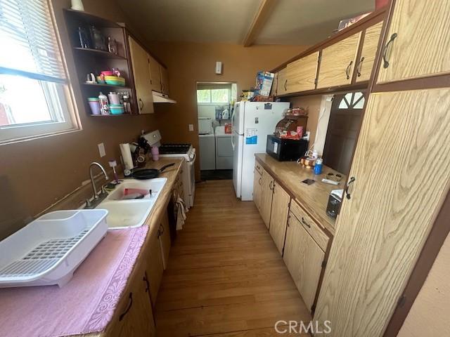 1815 W 9th St, Pomona, CA 91766 - kitchen featuring washing machine and dryer, white appliances, light wood finished floors, a sink, and under cabinet range hood