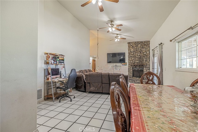 38740 25th St E, Palmdale, CA 93550 - dining room with vaulted ceiling, a ceiling fan, light tile patterned floors, and a stone fireplace