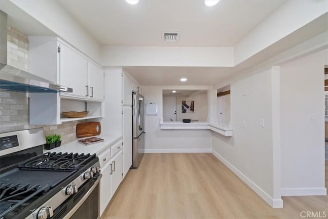 18710 Corwin Rd, Apple Valley, CA 92307 - kitchen with appliances with stainless steel finishes, wall chimney range hood, light wood-style flooring, white cabinetry, and baseboards