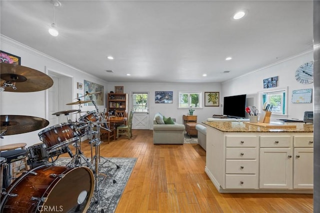 interior space featuring ornamental molding, open floor plan, white cabinetry, light wood-style floors, and light stone countertops
