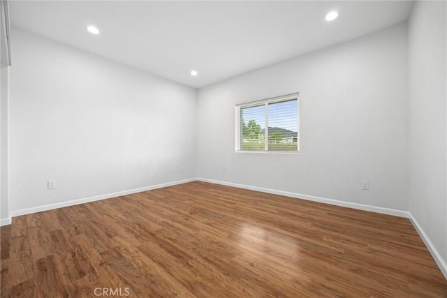 empty room featuring wood finished floors, baseboards, and recessed lighting
