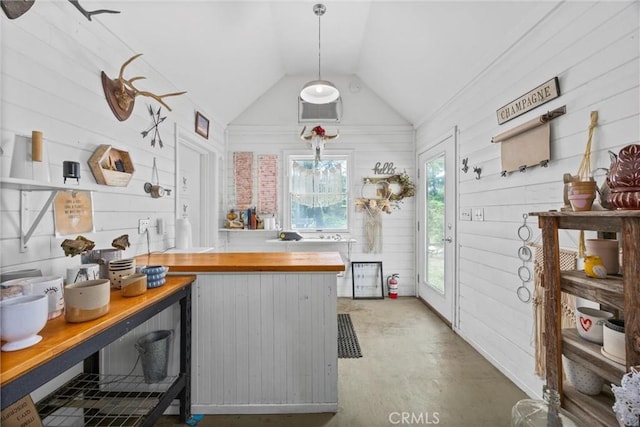 kitchen featuring wood counters, vaulted ceiling, concrete floors, wooden walls, and a peninsula