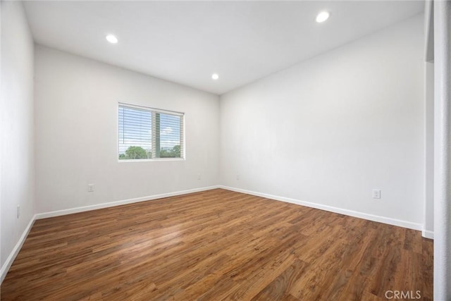 empty room with wood finished floors, baseboards, and recessed lighting