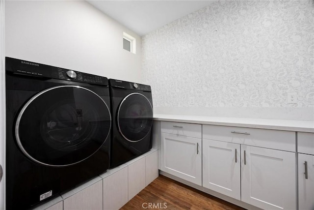 laundry area featuring washer and clothes dryer, cabinet space, and wood finished floors