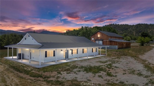back of property at dusk featuring metal roof, central air condition unit, and a patio area