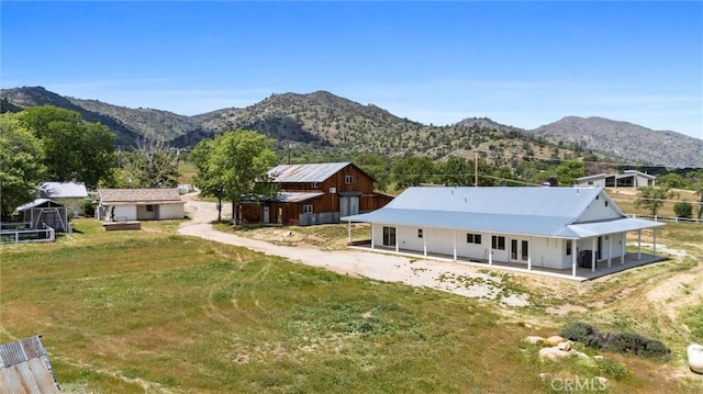 back of house with a mountain view, a yard, a storage unit, an outbuilding, and driveway