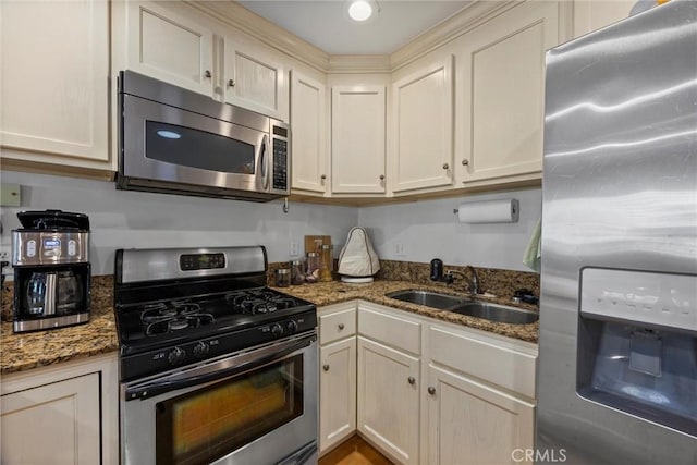 kitchen featuring appliances with stainless steel finishes, a sink, and dark stone countertops