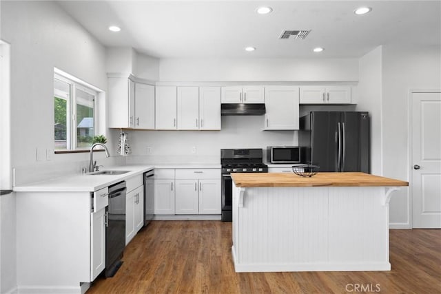 kitchen featuring black appliances, a sink, under cabinet range hood, white cabinets, and wooden counters