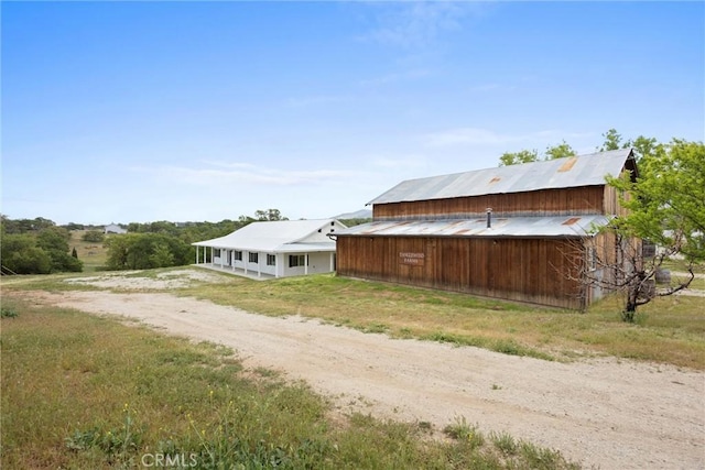 view of property exterior featuring dirt driveway and an outdoor structure