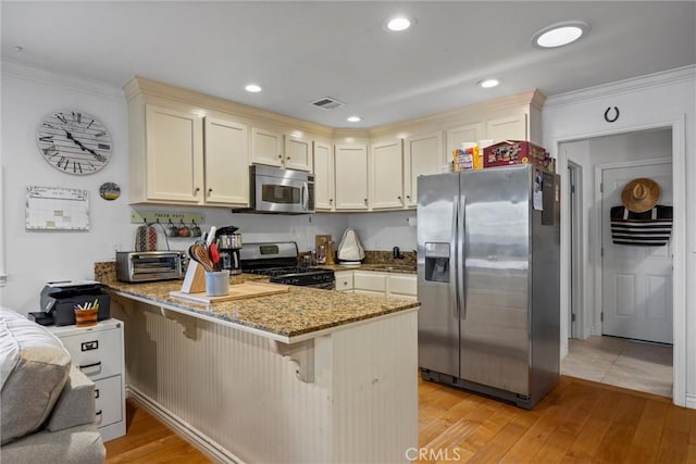 kitchen featuring appliances with stainless steel finishes, a peninsula, light wood-type flooring, ornamental molding, and light stone counters