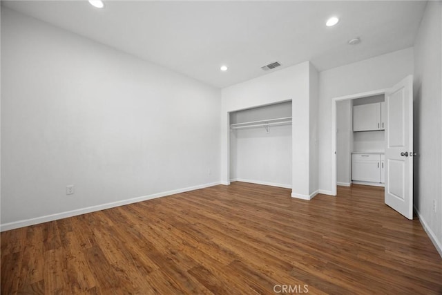 unfurnished bedroom featuring recessed lighting, dark wood-type flooring, baseboards, and a closet