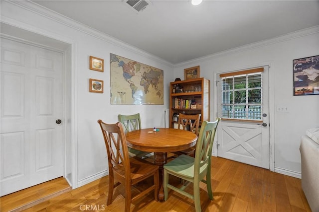 dining room featuring light wood-type flooring, crown molding, and baseboards